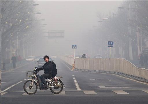 Male bicyclist riding across street in smog filled air
