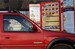 Car stopped at a fast food drive thru menu board