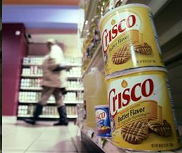 Two cans of Crisco shortening sitting on grocery shelf.