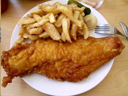 Fish and chips meal on a plate all brownish yellow in color.