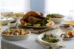 Thanksgiving meal with turkey and many side dishes on table.