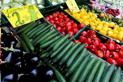 Colorful vegetables - cucumbers, red and yellow pepppers, and eggplant displayed at market.