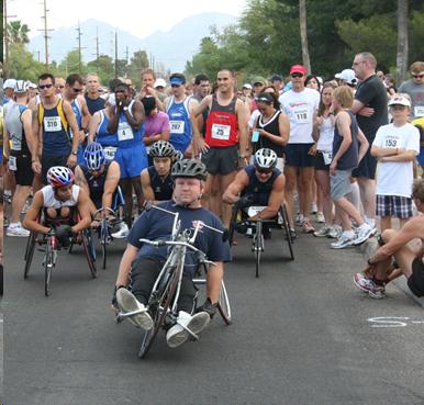 Group of racers getting ready for a running race with wheelchair racers at the front of the pack.