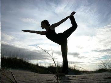 Woman, appears as silhouette, doing a yoga pose outdoors