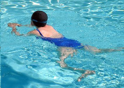 Woman swimming breaststroke in pool.